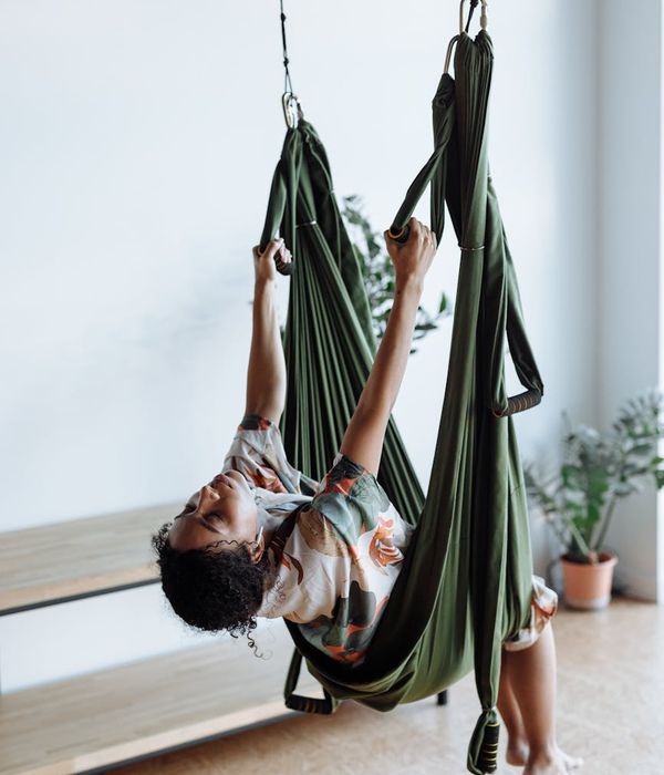 A young person doing a tree yoga pose in a bright, modern studio.