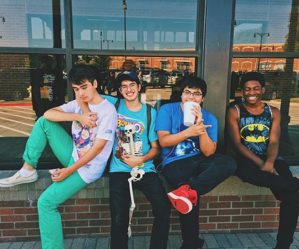 Group of diverse teenagers sitting together and smiling in a comfortable setting.